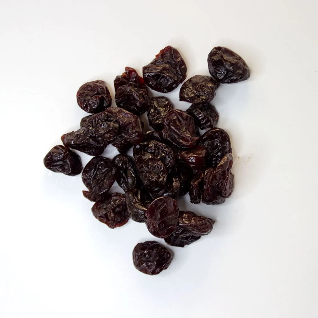 Traina® Dried Tart Cherries, sweetened, Pitted, whole - small pile of dried fruit on white background.
