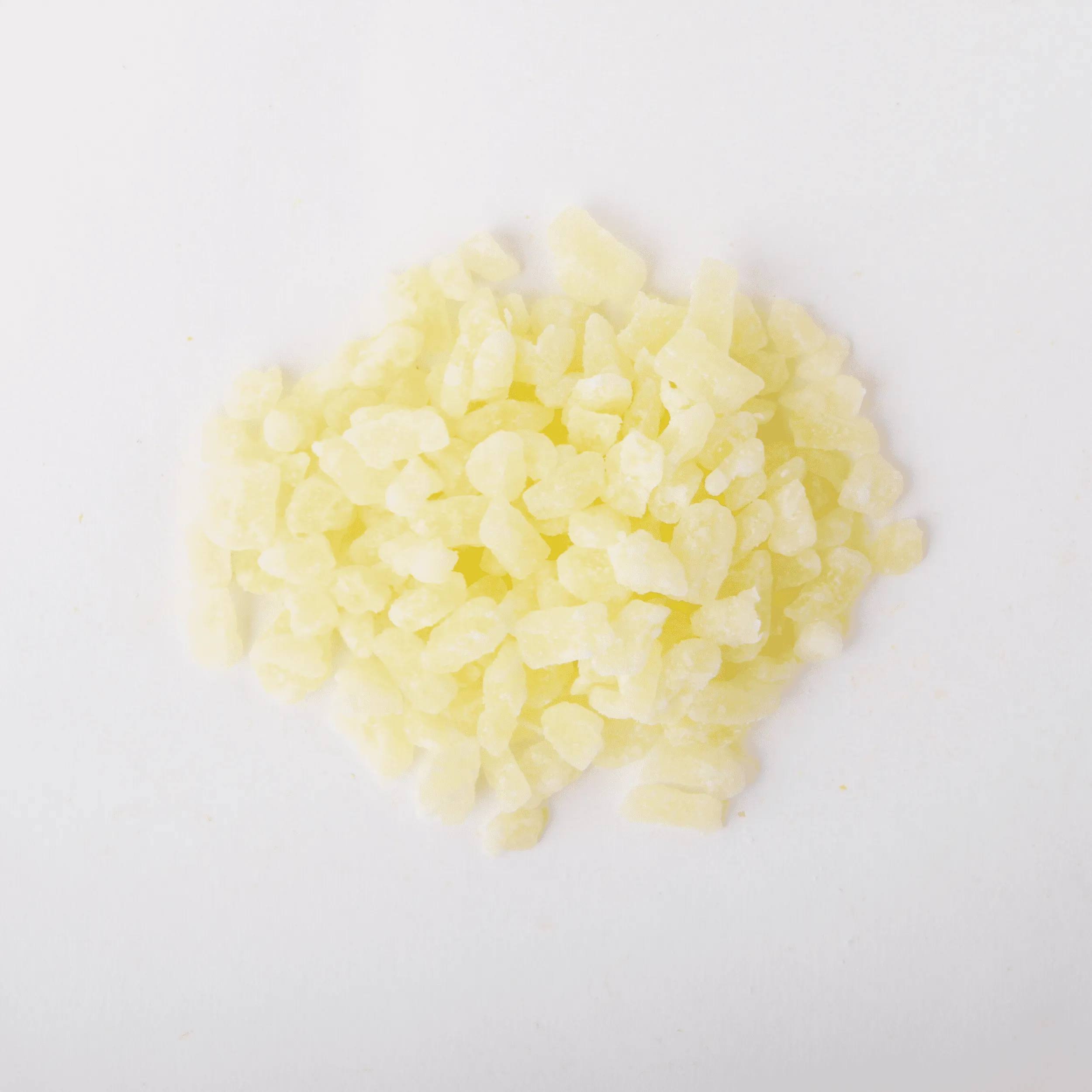 Traina® Dried Pineapple, Sweetened, with Sulfur, diced 5-7 mm - small pile of dried fruit on white background.