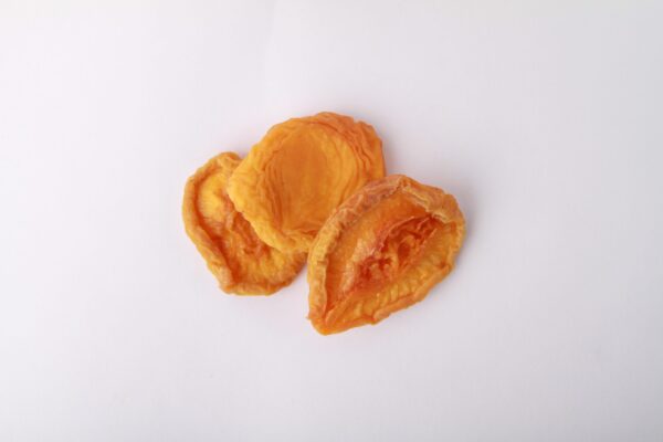 Traina® Dried Peaches, Extra Choice halves- small pile of sun dried fruit on white background.