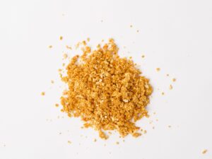 Traina® Natural Dried Tangerine, granules - small pile of dehydrated fruit on white background