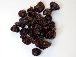Traina® Dried Tart Cherries, sweetened, whole - small pile of sun dried fruit on white background.