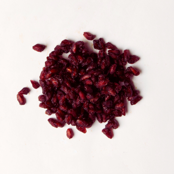 Traina® Dried Pomegranate Aril, Sweetened - small pile of dried fruit on white background.